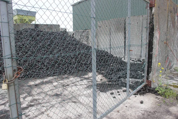 金網ゲートの背後に briquets 石炭の堆積 — ストック写真