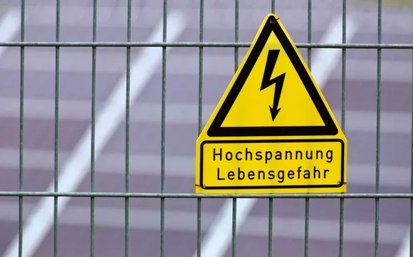 Firma con le parole Alta tensione - Pericolo per la vita in tedesco di fronte ai pannelli solari — Foto Stock