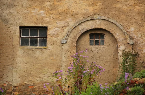 Оштукатурена стіна з аркою і вікном на межі розкладених квітів — стокове фото