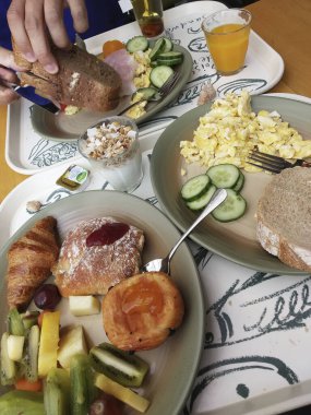 Belçika, Brüksel - 05 Haziran 2019: Oteldeki masada oturan adam kahvaltı yapıyor. Eller ve masa servisi yakın çekim..