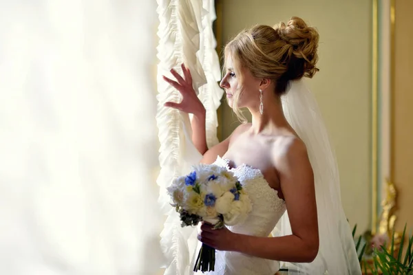 Noiva de beleza em vestido de noiva com buquê e véu de renda dentro de casa — Fotografia de Stock