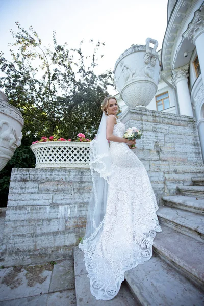 Belleza novia en vestido de novia con ramo y velo de encaje en la naturaleza —  Fotos de Stock