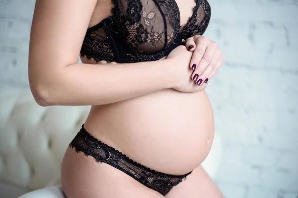 Closeup mooie zwangere dame in elegante pose in zwarte beha en slipje — Stockfoto