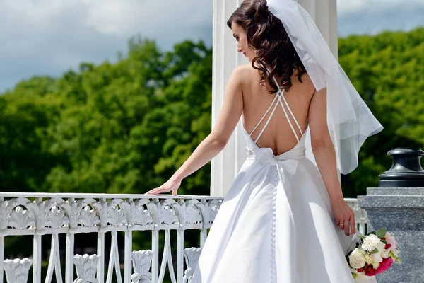 Bruid van de schoonheid in bruidsjurk met boeket en kantpatroon sluier in de natuur — Stockfoto