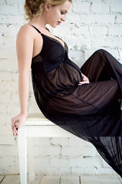 Крупный план красивая беременная женщина в элегантной позе в платье — стоковое фото