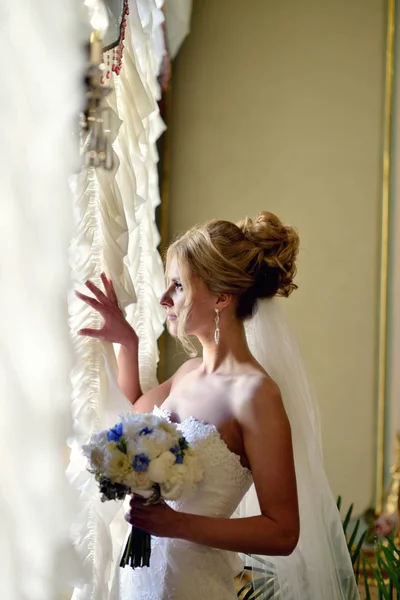 Noiva de beleza em vestido de noiva com buquê e véu de renda dentro de casa — Fotografia de Stock