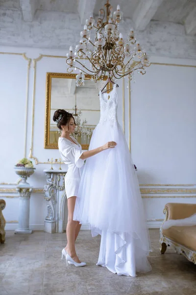 Bella sposa in accappatoio sta guardando un abito da sposa — Foto Stock