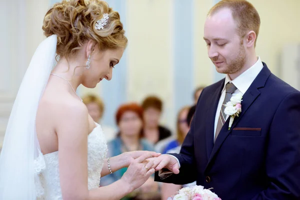 Noiva de beleza e noivo bonito estão usando anéis uns aos outros — Fotografia de Stock