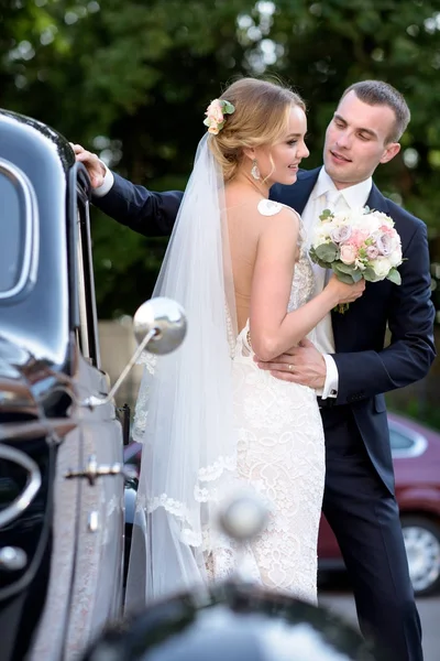 Çift düğün birbirlerine sarılıyor bir araba — Stok fotoğraf