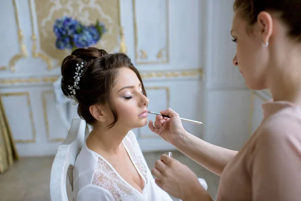 Artista de maquiagem de casamento fazendo uma maquiagem para a noiva — Fotografia de Stock