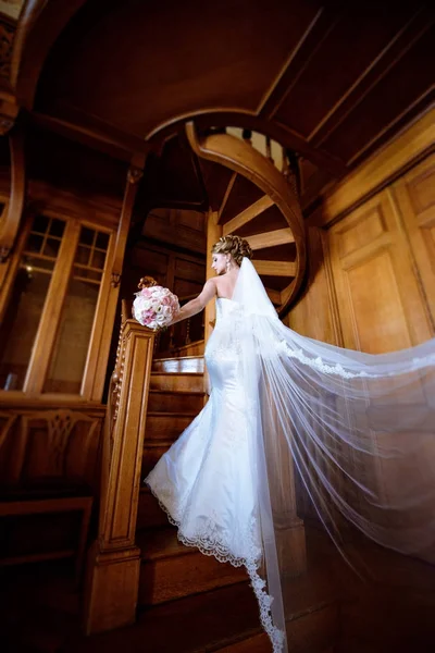 Schoonheid bruid in bruidsjurk met boeket en kantpatroon sluier binnenshuis — Stockfoto