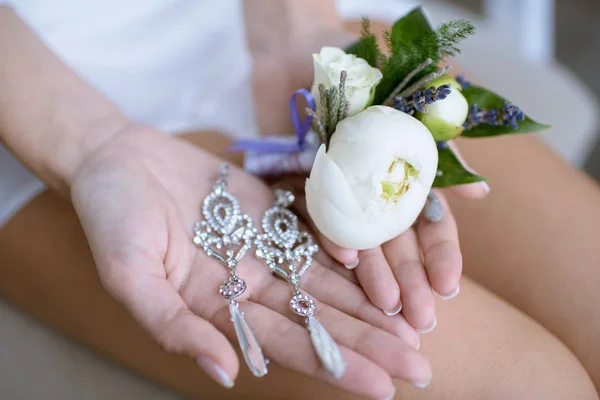 白いウェディング ドレスの美しい花嫁は彼女の手でピアスを保持しています。 — ストック写真
