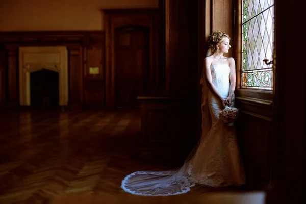 Piękna panna młoda w sukni ślubnej z bukiet i Koronka welon pomieszczeniu — Zdjęcie stockowe
