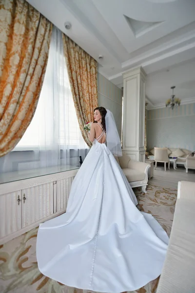Краса нареченої в весільній сукні з букетом і мереживною фатою в приміщенні — стокове фото