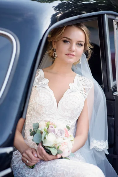 Краса нареченої в весільній сукні з букетом і мереживною фатою в машині — стокове фото