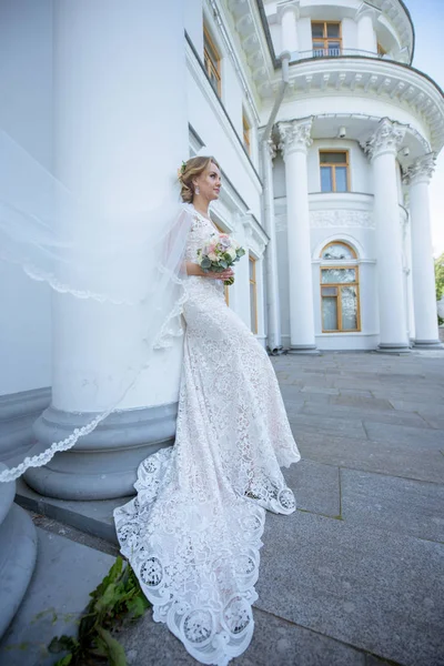 Краса нареченої в весільній сукні з букетом і мереживною фатою на природі — стокове фото