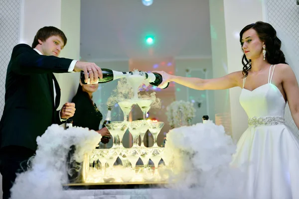 Beautiful wedding couple is pouring champagne indoors — Stock Photo, Image