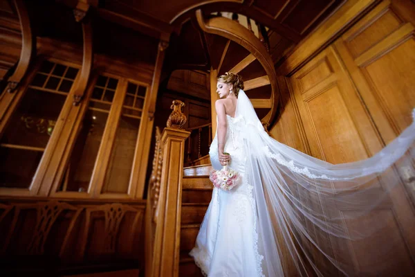 Невеста в свадебном платье с букетом и кружевной вуалью в помещении — стоковое фото