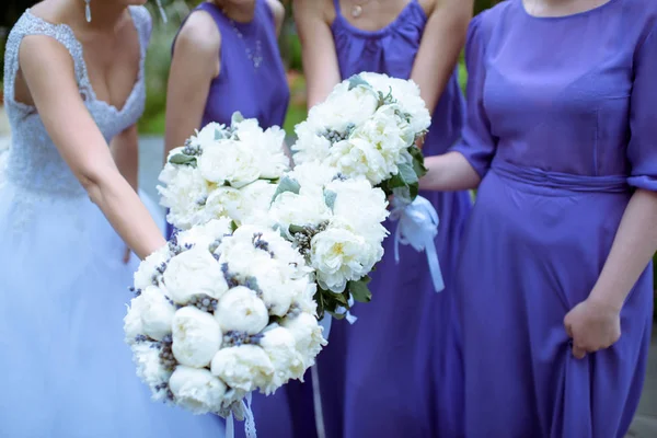 Belas damas de honra e noiva em vestido de noiva com buquês na natureza — Fotografia de Stock