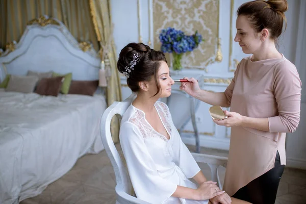 Artista de maquiagem de casamento fazendo uma maquiagem para a noiva — Fotografia de Stock