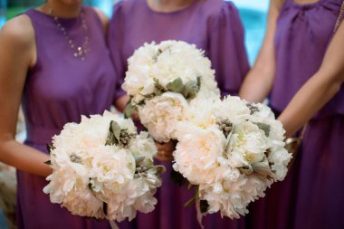 Güzel nedime ve gelinlik elbisesi içinde gelin buketleri doğa ile