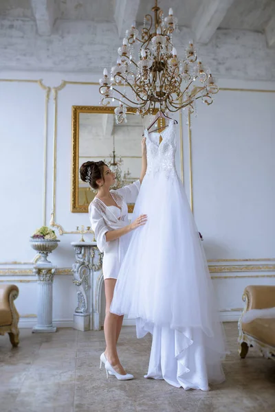 Bella sposa in accappatoio sta guardando un abito da sposa — Foto Stock