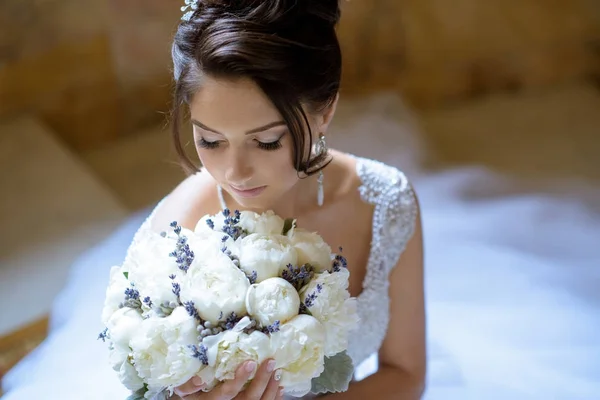 Beauty bride in bridal gown with bouquet and lace veil indoors — Stock Photo, Image