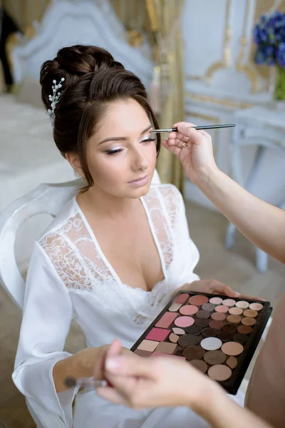 Artista de maquiagem de casamento fazendo uma maquiagem para a noiva — Fotografia de Stock