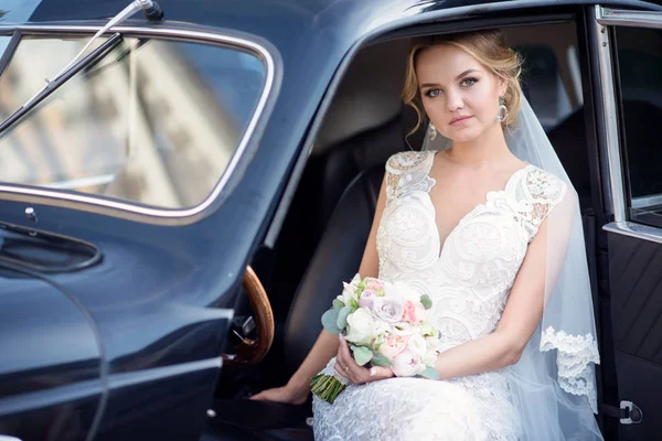 Краса нареченої в весільній сукні з букетом і мереживною фатою в машині — стокове фото