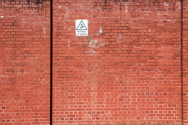 Τοίχος κόκκινο τούβλο με ένα προειδοποιητικό σημάδι — Φωτογραφία Αρχείου