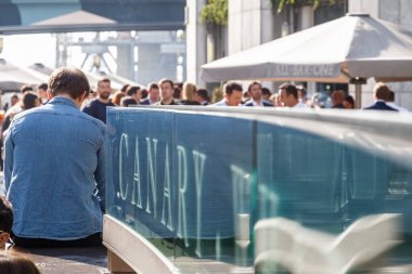 Bir liman içme kişilik bir kalabalık Canary Wharf işaretiyle 