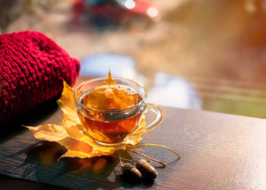 Sonbahar Natürmort: Akçaağaç çay pencerenin yakınındaki ahşap bir masa üzerinde bırakır. Güneş ışınları üzerinde demlenmiş çay. Güneşli bir pencere arka plan üzerinde sıcak çay.