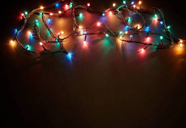 Jul bakgrund med ljus och fritt textutrymme. Julbelysning gränsen. Glödande färgglada julbelysning på svart bakgrund. Nytt år. Julen. Inredning. Jordgubbar. — Stockfoto