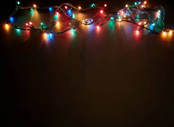 Christmas background with lights and free text space. Christmas lights border. Glowing colorful Christmas lights on black background. New Year. Christmas. Decor. Garland.