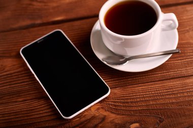 Kahve ve cep telefonu. Smartphone ve bir fincan espresso ahşap bir masa üzerinde. Belgili tanımlık becerikli alet. Kahve evi. Cafe.