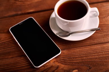 Kahve ve cep telefonu. Smartphone ve bir fincan espresso ahşap bir masa üzerinde. Belgili tanımlık becerikli alet. Kahve evi. Cafe.