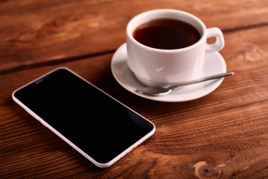 Kahve ve cep telefonu. Smartphone ve bir fincan espresso ahşap bir masa üzerinde. Belgili tanımlık becerikli alet. Kahve evi. Cafe.