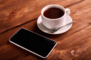 Kahve ve cep telefonu. Smartphone ve bir fincan espresso ahşap bir masa üzerinde. Belgili tanımlık becerikli alet. Kahve evi. Cafe.
