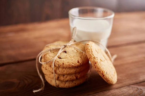Cookie-k és a tej. Csokoládé chip cookie-kat és egy pohár tejet. Szüreti külsőt. Ízletes sütik és pohár tejet, rusztikus, fából készült háttér. Ételek, gyorsétel, gasztronómiai, sütés és étkezési koncepció — Stock Fotó