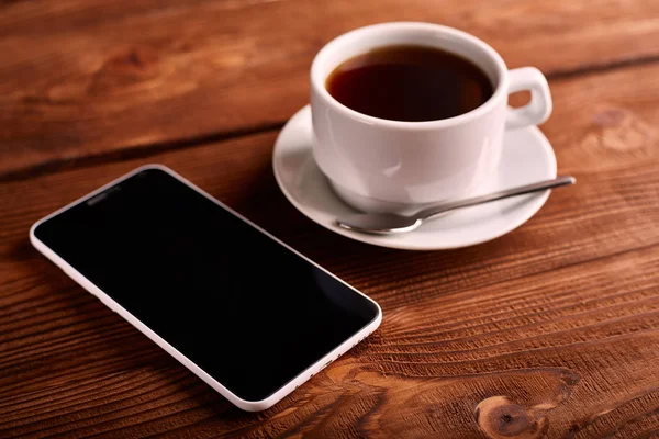Кава та мобільний телефон. Смартфон і чашка еспресо на дерев'яному столі. Гаджет. Кав'ярня. Кафе . — стокове фото