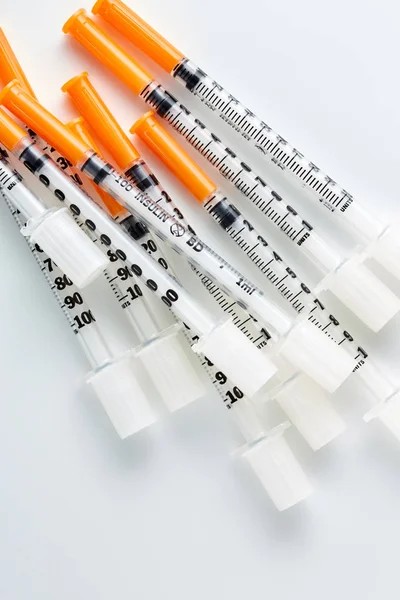 Tre siringhe di insulina isolate su fondo bianco. Un mucchio di siringhe mediche. Siringa singola per insulina con cappuccio arancione . — Foto Stock