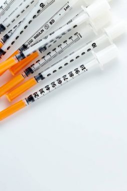 Üç insülin izole üzerinde beyaz arka plan batar. Tıbbi şırınga yığını. Tek insülin şırınga turuncu kap ile.