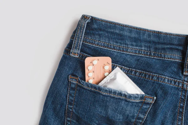 Condoms in package in jeans. Safe sex concept. Healthcare medicine, contraception and birth control. Close Up oral contraceptive pills. Protection against unwanted pregnancy. Protection against AIDS