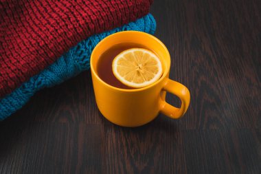 Limonlu sıcak çay örme sıcak kış eşarp, sıcak örme Kazak veya battaniye giyinmiş. bir eşarp ve limon ile çay natürmort. Kış zamanı. Rahat ve yumuşak kış arka plan.