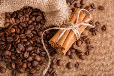 Kahve çekirdekleri ve tarçın çuval bezi bir arka plan üzerinde. Kavrulmuş kahve çekirdekleri arka plan kapatın. Üst metin kopyalama yeri olan kahve çekirdekleri kazık. Baharat. Baharat. Tarçın. Badian. Kahve evi.
