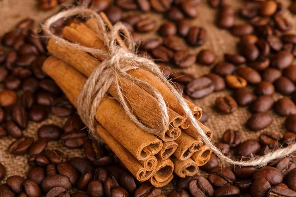 Kahve çekirdekleri ve tarçın çuval bezi bir arka plan üzerinde. Kavrulmuş kahve çekirdekleri arka plan kapatın. Üst metin kopyalama yeri olan kahve çekirdekleri kazık. Baharat. Baharat. Tarçın. Badian. Kahve evi.