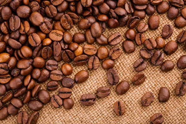 kahve çekirdekleri çuval bezi arka plan üzerinde. kavrulmuş kahvenin beyaz arka planda izole. Kavrulmuş kahve çekirdekleri arka plan kapatın. Kahve çekirdekleri kazık kopya alanı metin için beyaz zemin üzerine üstten