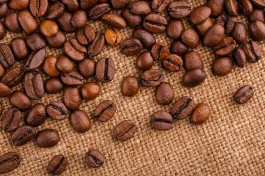kahve çekirdekleri çuval bezi arka plan üzerinde. kavrulmuş kahvenin beyaz arka planda izole. Kavrulmuş kahve çekirdekleri arka plan kapatın. Kahve çekirdekleri kazık kopya alanı metin için beyaz zemin üzerine üstten