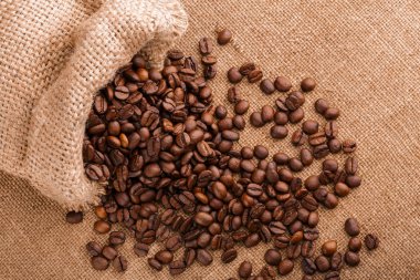 kahve çekirdekleri çuval bezi arka plan üzerinde. kavrulmuş kahvenin beyaz arka planda izole. Kavrulmuş kahve çekirdekleri arka plan kapatın. Kahve çekirdekleri kazık kopya alanı metin için beyaz zemin üzerine üstten