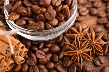 Kahve çekirdekleri ve tarçın çuval bezi bir arka plan üzerinde. Kavrulmuş kahve çekirdekleri arka plan kapatın. Üst metin kopyalama yeri olan kahve çekirdekleri kazık. Baharat. Baharat. Tarçın. Badian. Kahve evi.